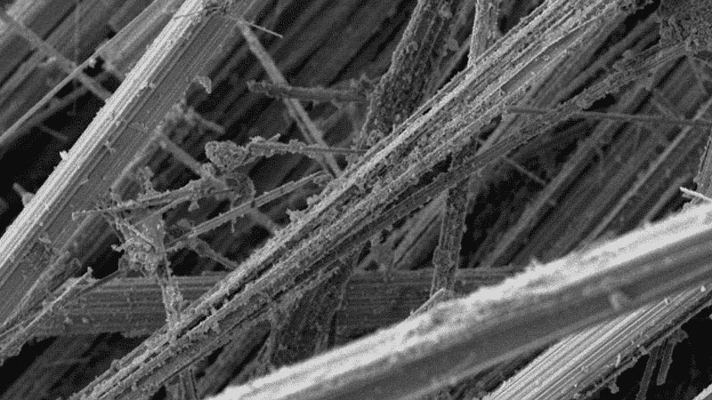 Close-up van vezelstructuur onder elektronenmicroscoop, toont verweven asbestvezels met ruwe textuur, gebruikt voor analyse bij asbestinventarisatie