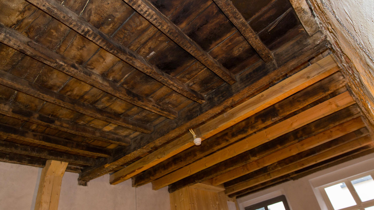 Plafond met houten balken en hanglamp in oude fabriek, illustratie van bouwkundige staat bij asbestonderzoek in de Puddingfabriek