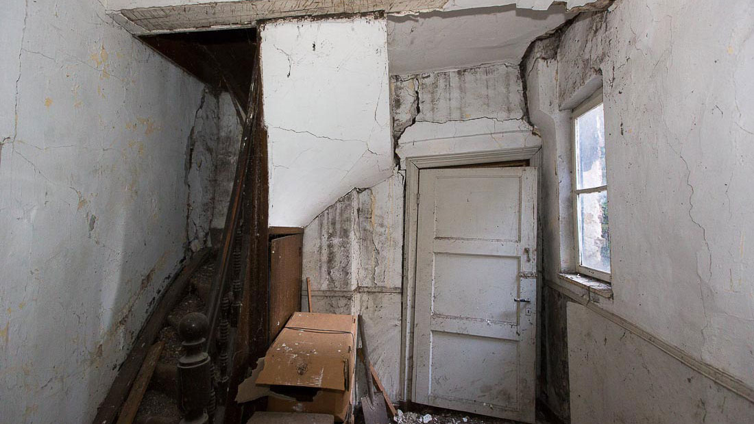 Vervallen interieur met houten trap en beschadigde muren, illustratie van asbestonderzoek en bouwkundige analyse in de Puddingfabriek