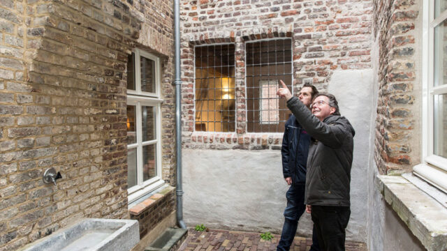 Inspectie in binnenplaats van oude fabriek, met aandacht voor mogelijke asbestbronnen in muren en dakconstructie