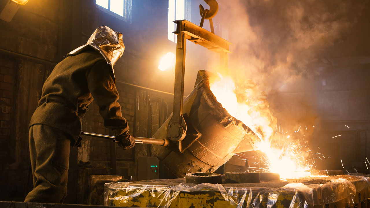 Werknemer giet vloeibaar metaal in mal in industriële omgeving met beschermende uitrusting en veiligheidsmaatregelen