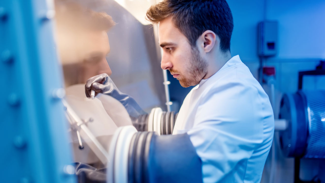 Laboratoriummedewerker werkt met handschoenkast voor veilige analyse van gevaarlijke stoffen