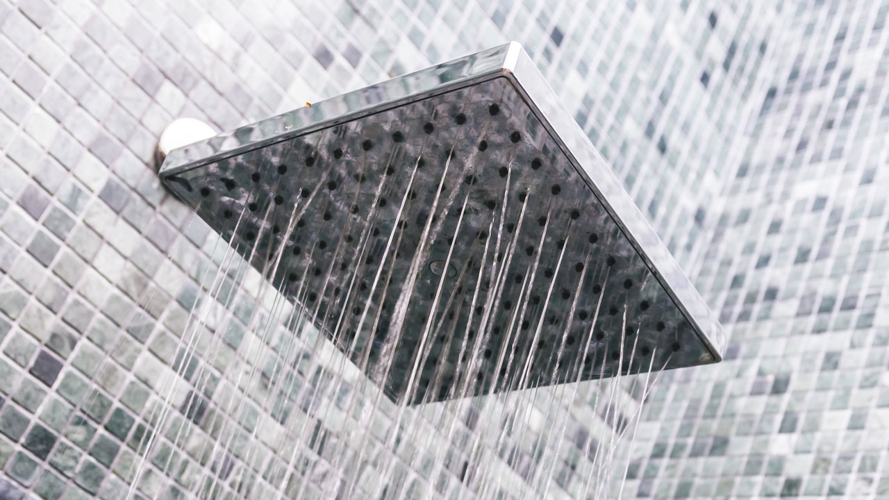 Stromend water uit moderne douchekop – visuele verwijzing naar legionella-vrij douchen en veilige sanitaire installaties