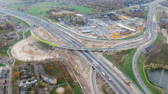 Luchtfoto van knooppunt in aanbouw met wegen, voertuigen en bouwactiviteiten, passend bij maatvoering in infrastructurele projecten