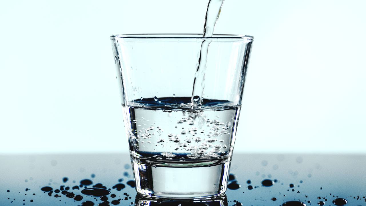 Vullen van glas met water – visuele verwijzing naar drinkwaterkwaliteit en legionella-risicoanalyse volgens NEN 1006