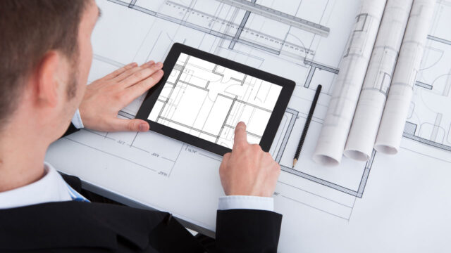 Man met tablet en bouwtekeningen, visualisatie van digitaal tekeningenbeheer en informatiemanagement in de bouwsector
