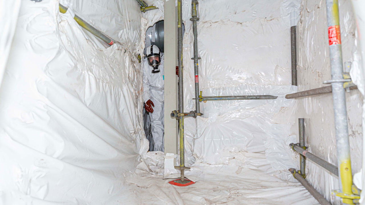 Medewerker in beschermpak en ademhalingsmasker in besloten ruimte, illustratie van veilig werken en blootstellingsbewaking