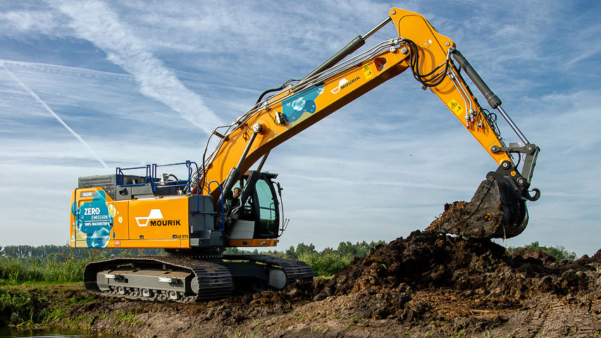Mourik graafmachine bij water, actief in grondverzet voor dijkversterking – onderdeel van project De Dijk van de Toekomst
