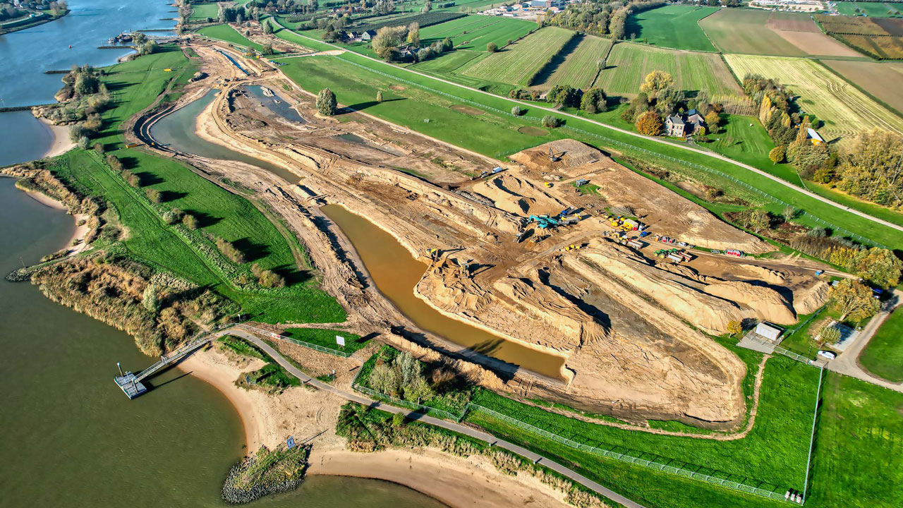 Luchtfoto dijkversterking met bouwactiviteiten en groene velden – onderdeel van project De Dijk van de Toekomst