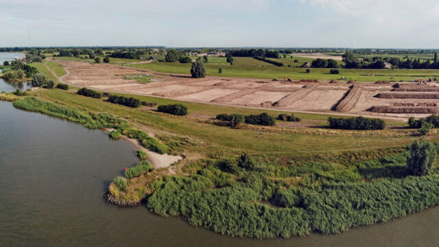Luchtfoto van dijkversterking en herinrichting Salmsteke met rivier, natuur en versterkte waterkering in beeld
