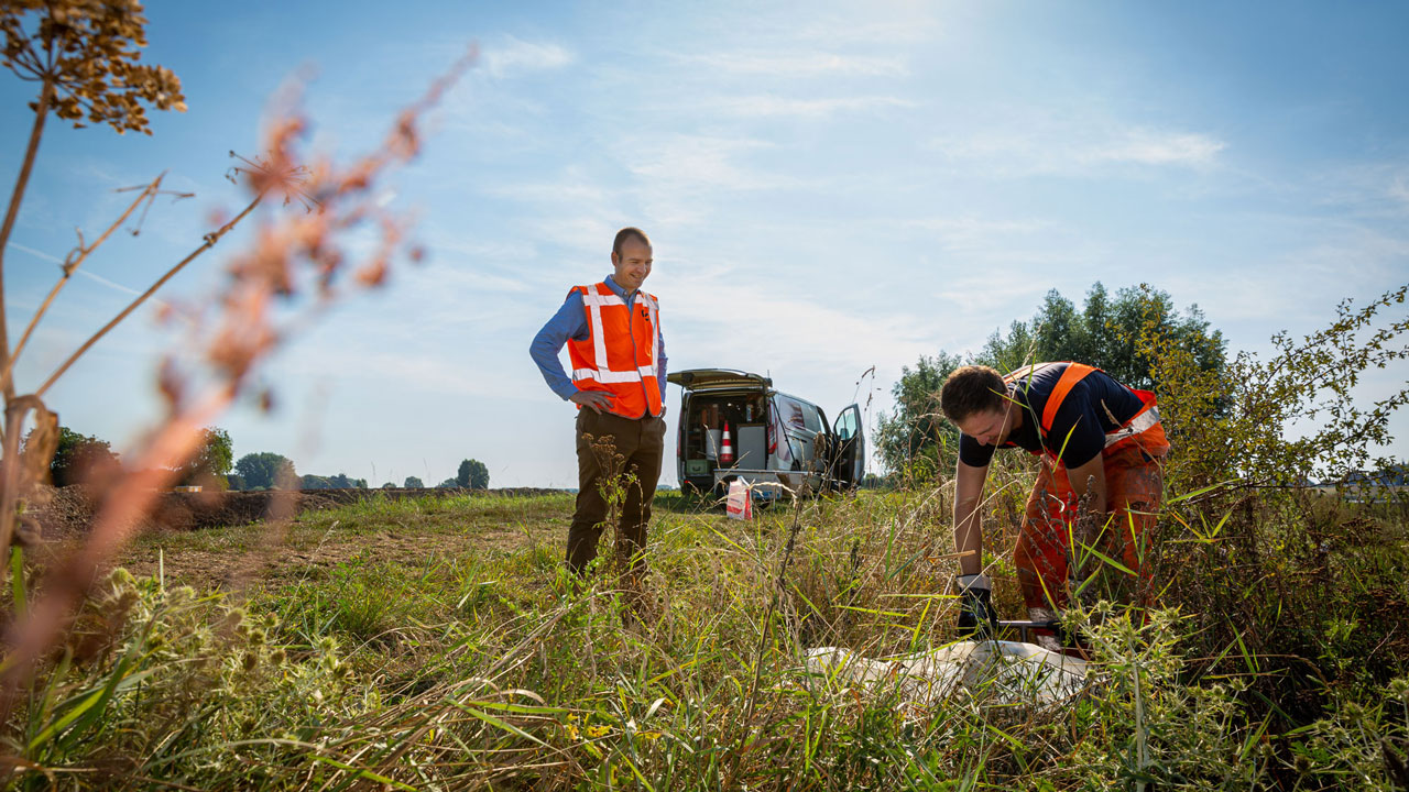 Adviseur waterveiligheid en grondwerker samen aan het werk op locatie