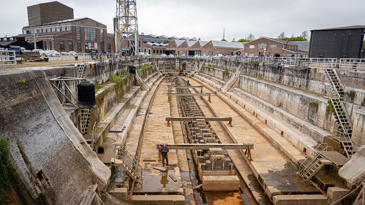 Leeg droogdok met houten balken en industriële achtergrond, illustratie van maritieme inspectie en onderhoudswerkzaamheden