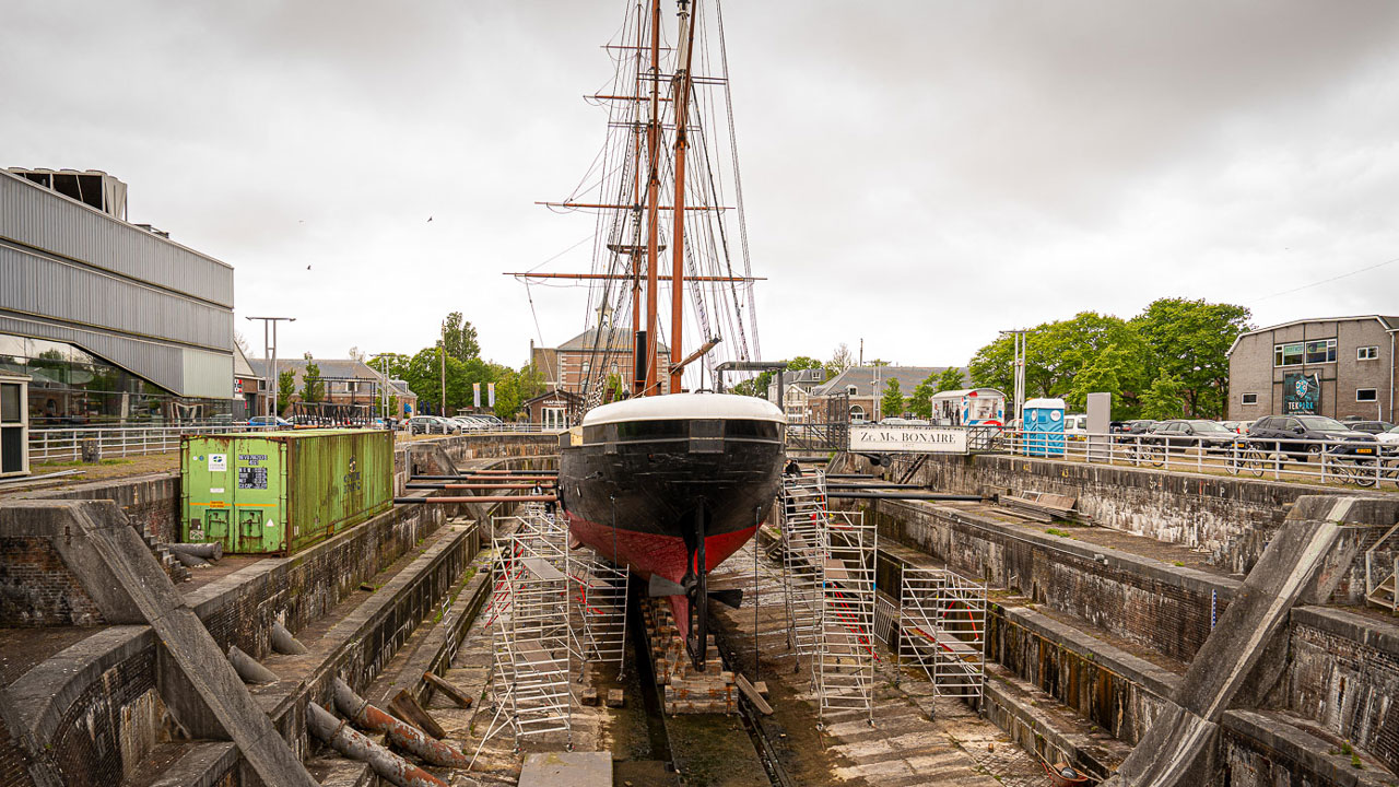 Groot schip in droogdok omringd door steigers en gebouwen, illustratie van maritieme inspectie en onderhoud