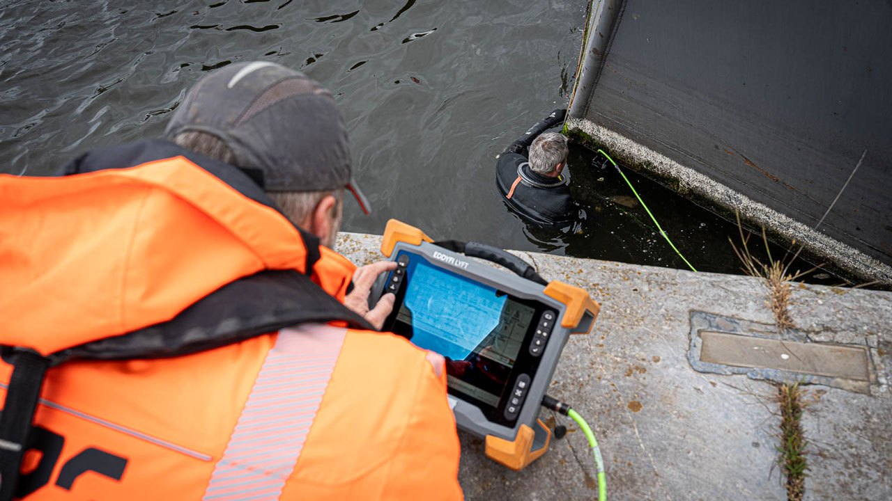 Inspectie onder water met meetapparatuur en duiker bij betonnen constructie, illustratie van veilig werken volgens RWS-richtlijnen