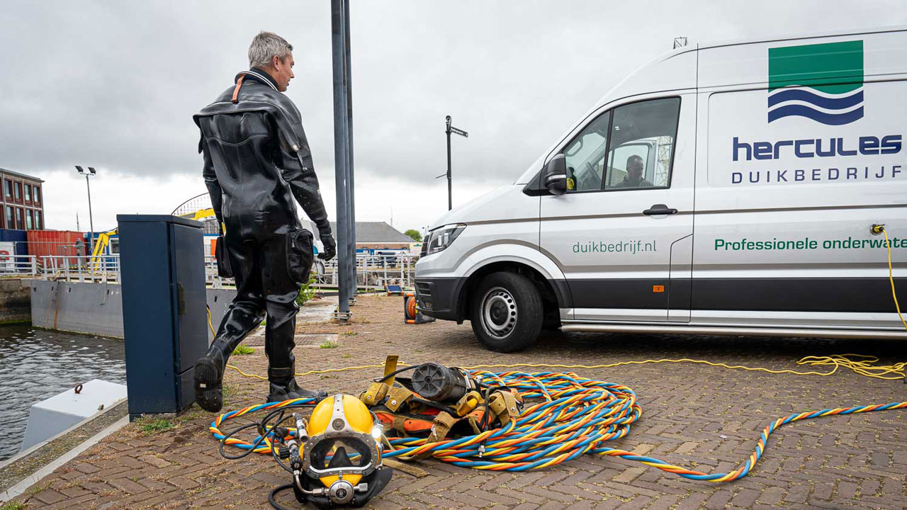 Duiker van Hercules bij waterkant met uitrusting en bus, symbool voor veilig en efficiënt werken onder water volgens RWS-kader