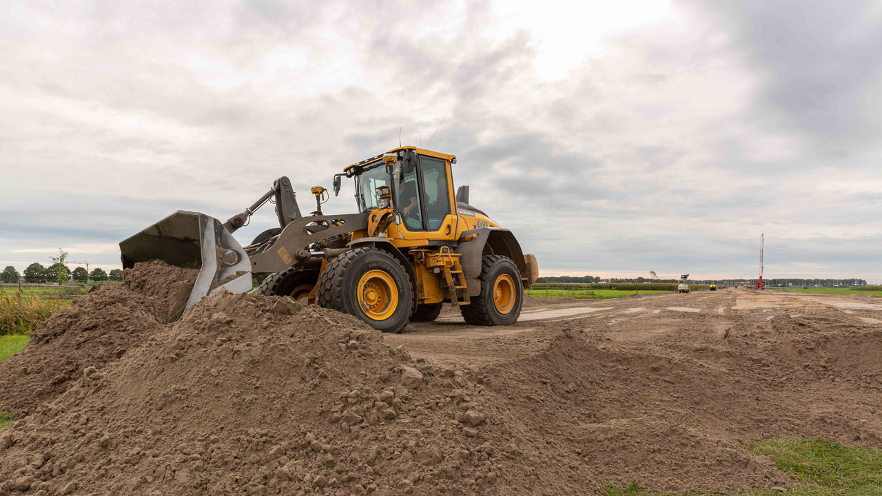 Voorlader verplaatst grond op bouwplaats Vredenburghlaan, onderdeel van duurzame aanbesteding en uitvoering