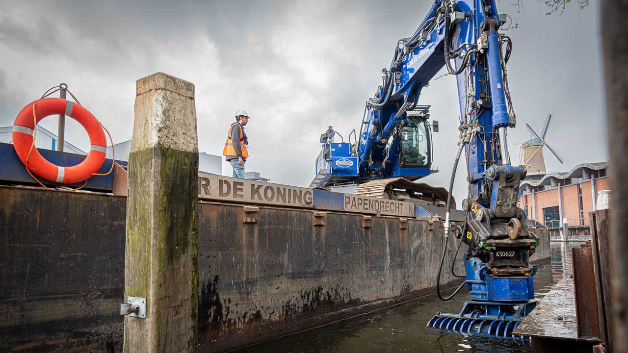 Werkzaamheden aan Hooikade met kraan op ponton en zicht op molen; Tetra Tech versterkt kadeconstructie met oog voor ruimte en historische elementen