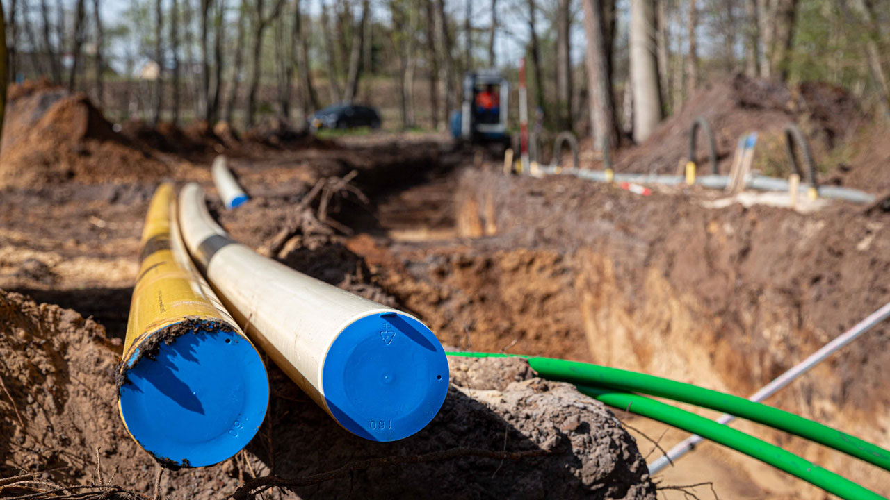 Gele en witte leidingen met blauwe doppen op bouwplaats N226, aanleg kabels en leidingen in bosrijke omgeving