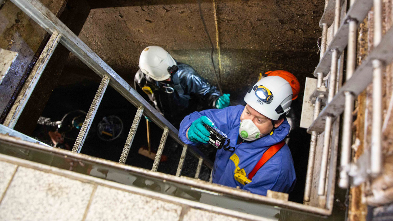 Medewerkers dalen af in rioolgemaal voor inspectie met specialistische apparatuur – focus op veiligheid en onderzoek
