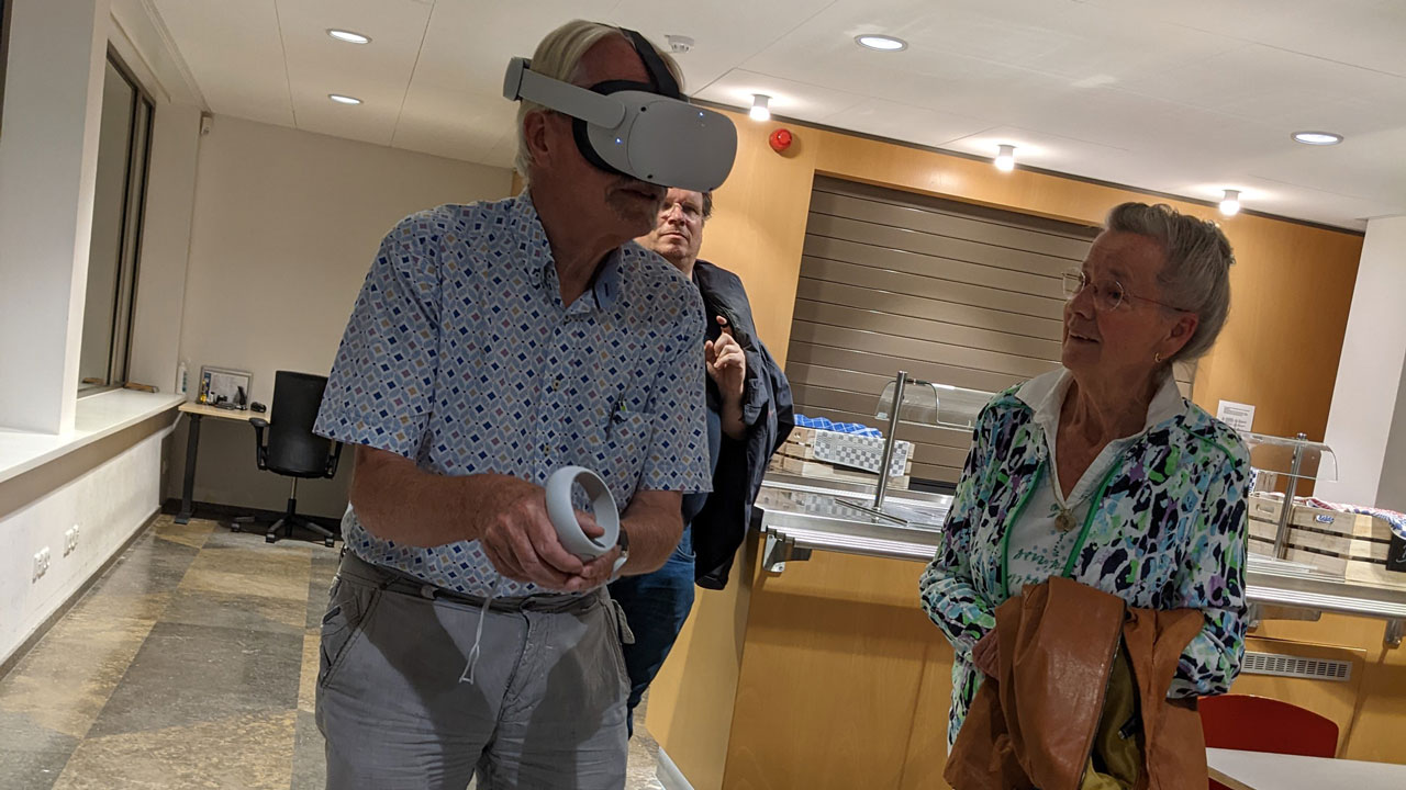 Bewoners ervaren stedelijke plannen via VR in participatiesessie, met headset en begeleiding in moderne ruimte met tafels en stoelen