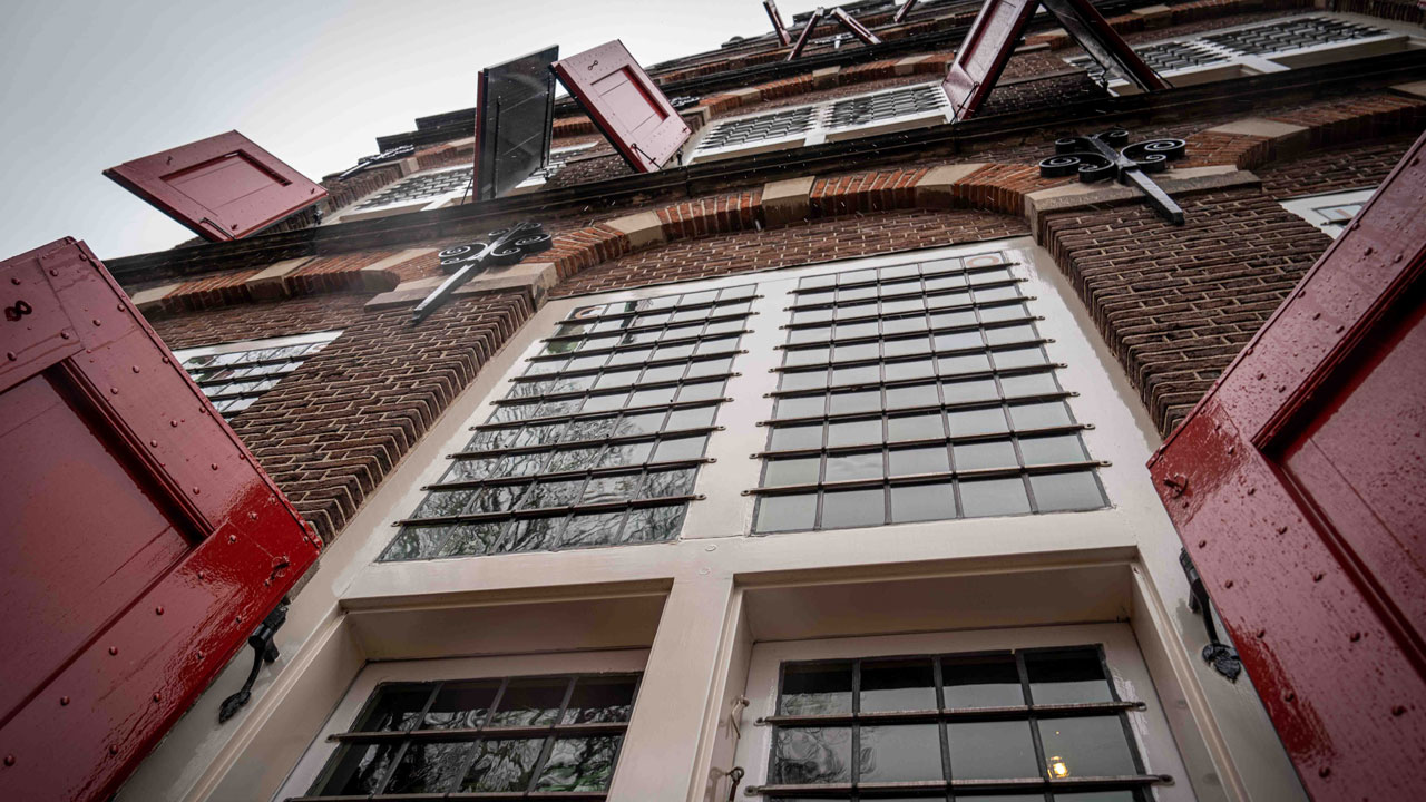 Buitenaanzicht van het Goudse Weeshuis met rode luiken en bakstenen gevel – vastgoedinspectie door Tetra Tech van rijksmonument in Gouda