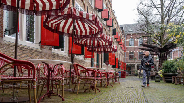Alphons van Dam voor het Goudse Weeshuis met rood-witte parasols en historische gevel – vastgoedopname door Tetra Tech van rijksmonument in Gouda
