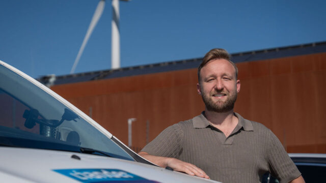 Foto van man voor gebouw met windmolen