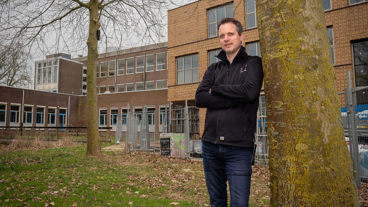 Man poseert voor nieuw schoolgebouw