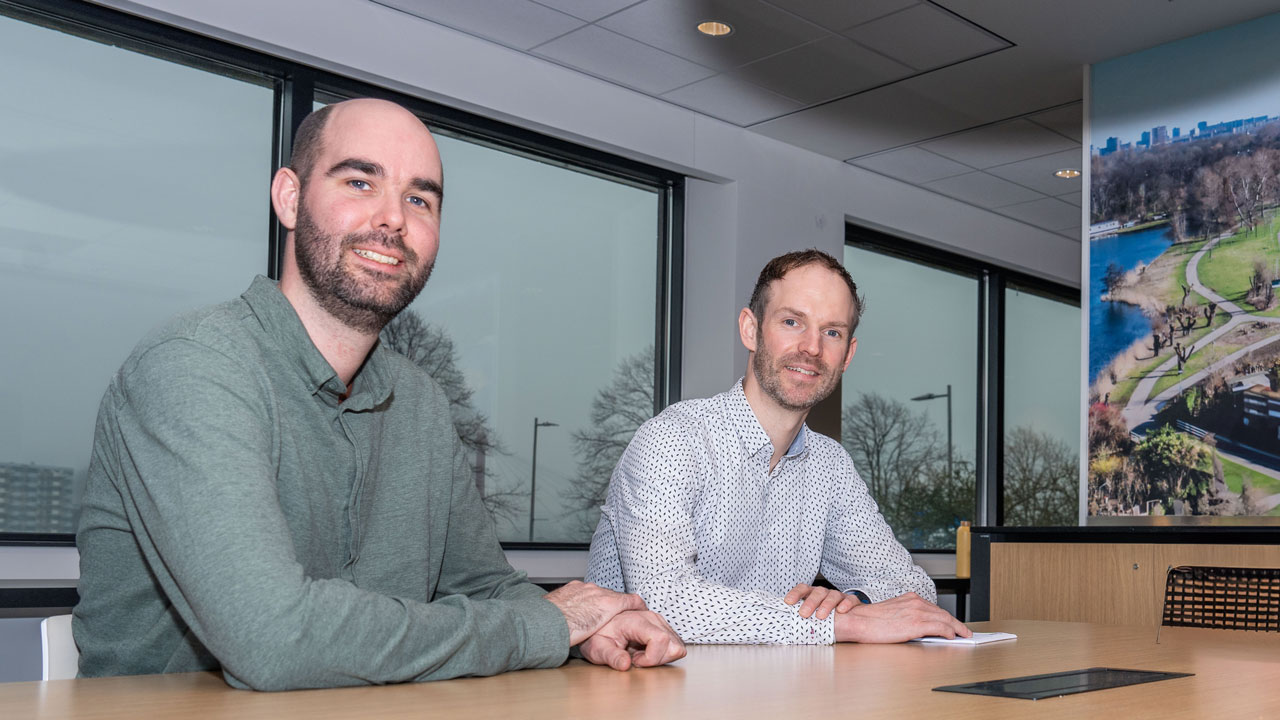 Twee mannen lachen en poseren terwijl zij in overleg zijn