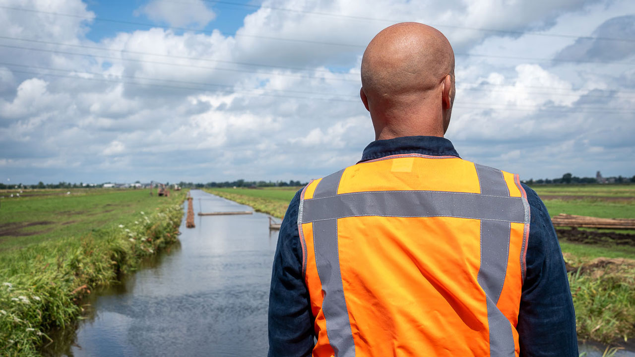 Medewerker observeert werkzaamheden aan overzijde van watergang in Krimpenerwaard voor aanleg van 2.250 hectare nieuwe veenweidenatuur