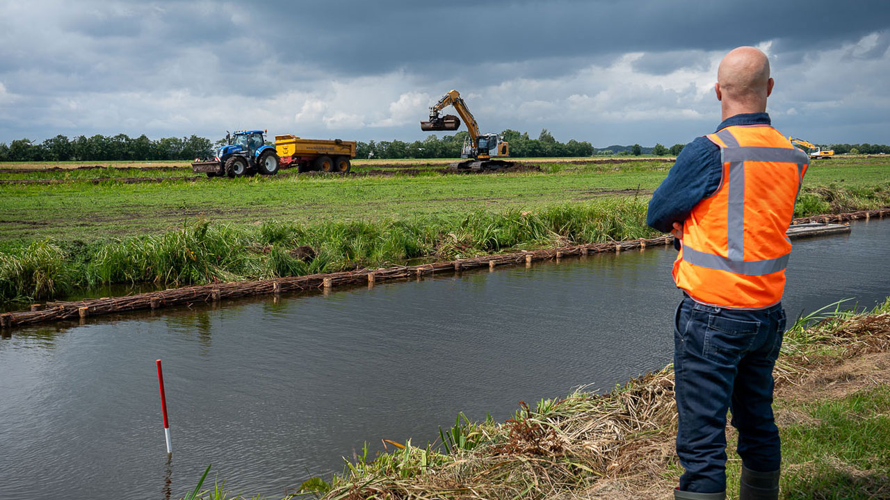 Medewerker bij watergang in veenweidegebied Krimpenerwaard; inzet voor 2.250 hectare nieuwe natuur en slim waterbeheer