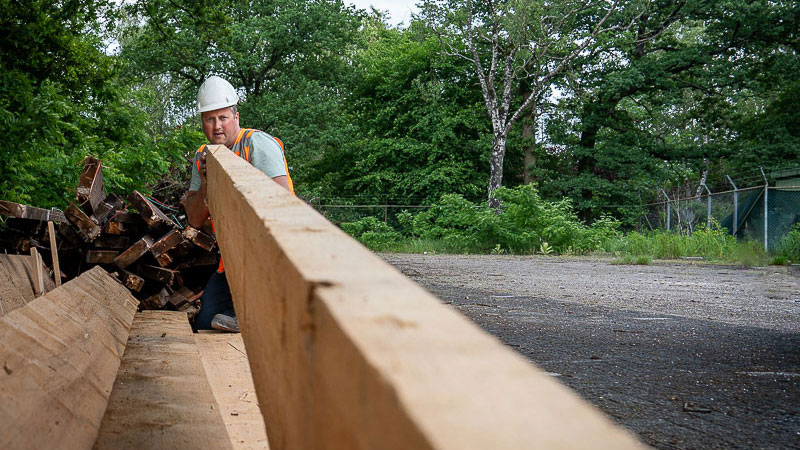Medewerker werkt met houten balken op buitenterrein – hergebruik van hout als onderdeel van circulair slopen in Nederland