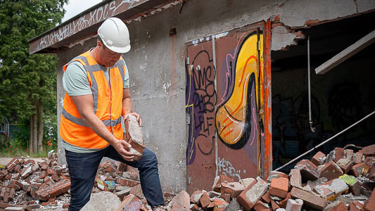 Medewerker met helm en baksteen tussen puin – circulair slopen met oog voor hergebruik en duurzame materiaalstromen
