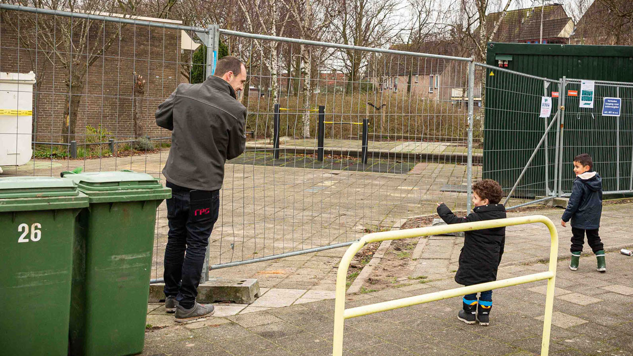 Volwassene en kinderen bij hekwerk tijdens circulaire sloop van schoolgebouw Sterrenwerk in opdracht van Gemeente Teylingen