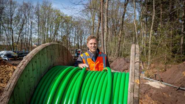 Tetra Tech-medewerker bij houten kabelhaspel in bosrijke omgeving, betrokken bij technische werkzaamheden in het veld