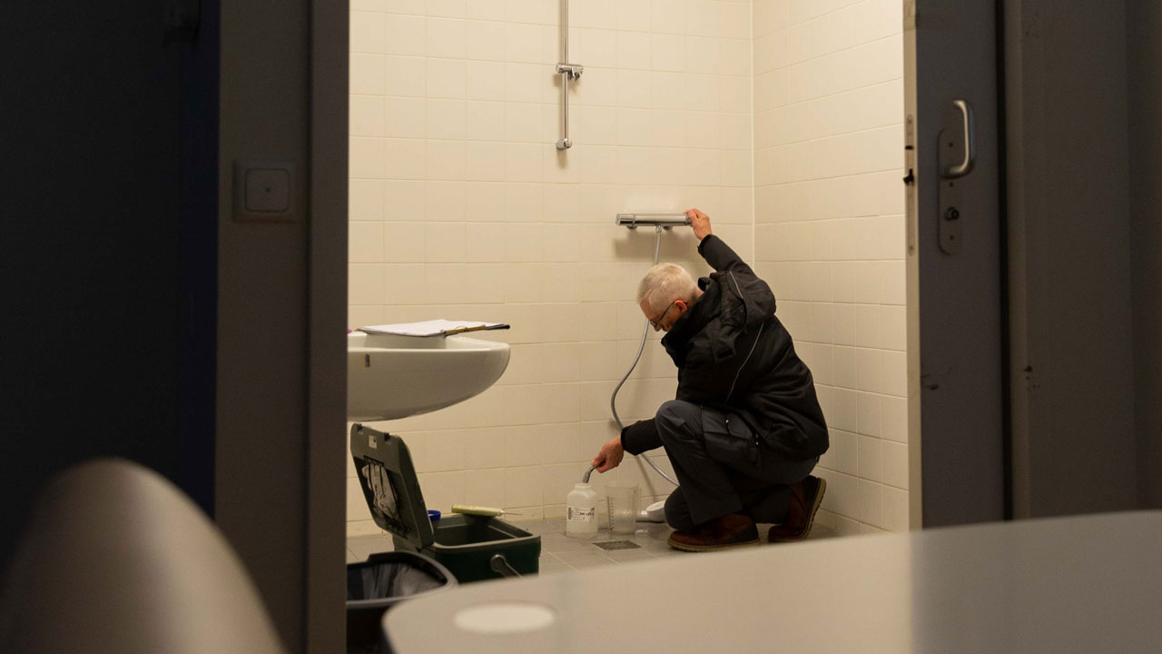 Technisch medewerker voert onderhoud uit in badkamer zorginstelling Amarant in kader van legionellapreventie