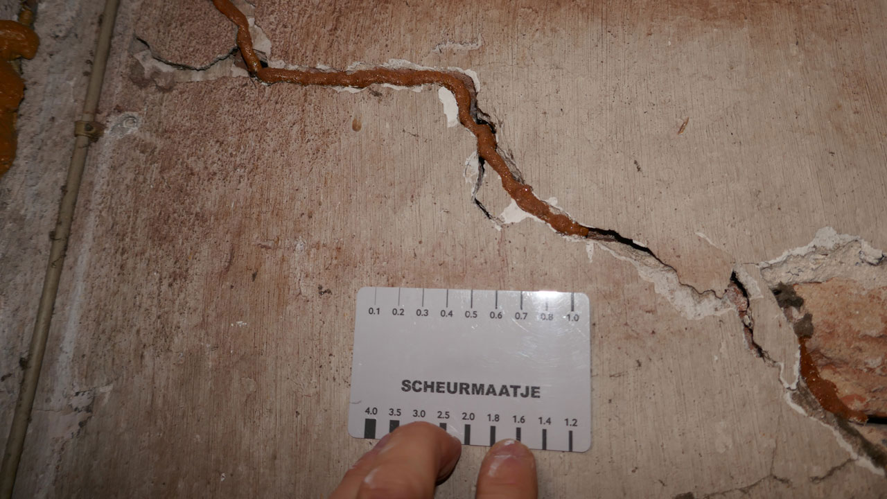 Scheur in muur met meetkaart