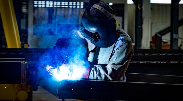 Lasser met helm en handschoenen aan het werk – blootstelling aan lasrook en vonken tijdens metaalbewerking