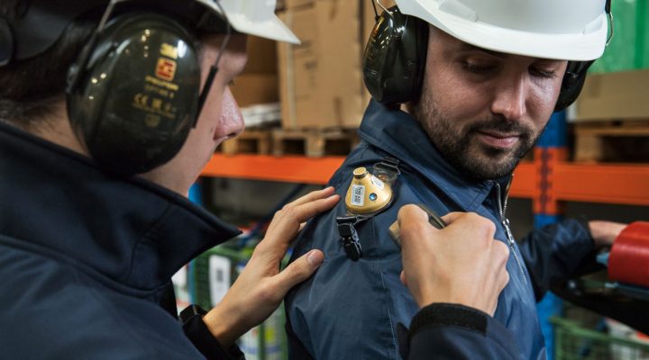 Arbeidshygiënist plaatst geluidsmeetapparatuur op schouder van medewerker voor meting blootstelling geluid