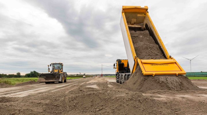 Bouwplaats Vredenburghlaan met vrachtwagen, bulldozer en windmolens, onderdeel van duurzame aanbesteding