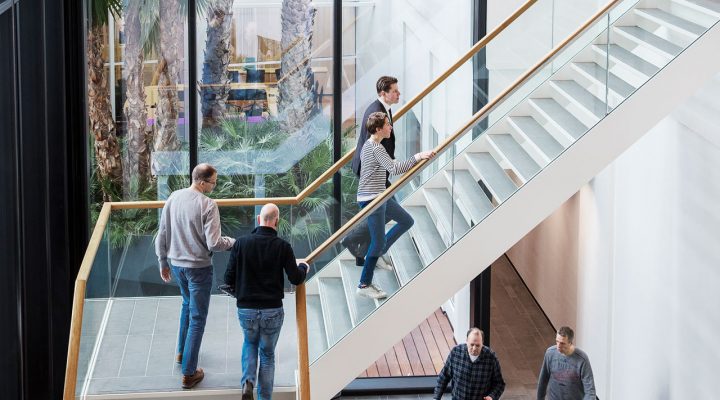 Modern kantoorpand met grote glazen gevel en trap. Mensen lopen de trap op