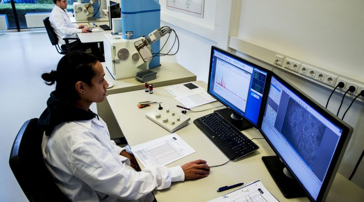 Laboratoriummedewerkers analyseren asbestmonsters met behulp van microscopen en specialistische software
