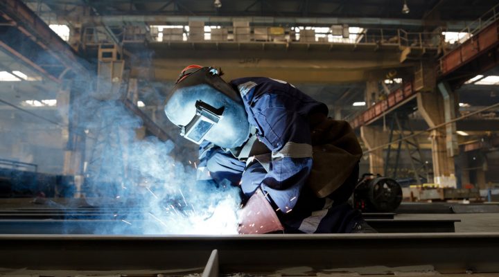 Werknemer last met beschermende uitrusting in industriële omgeving waar veilig omgaan met gevaarlijke stoffen essentieel is