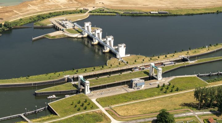 Luchtfoto van waterbouwkundig kunstwerk met sluizen en bedieningsgebouwen, essentieel voor waterbeheer en infrastructuur