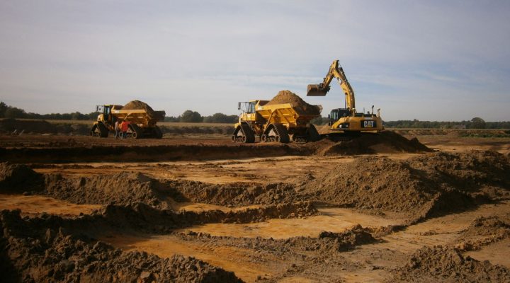 Grondverzet met CAT-graafmachine en dumpers in landelijk gebied. Werken aan duurzame inrichting van buitengebied