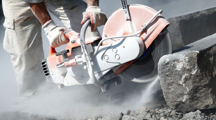 Bouwvakker zaagt beton met cirkelzaag – zichtbare kwartsstofemissie, risico op blootstelling