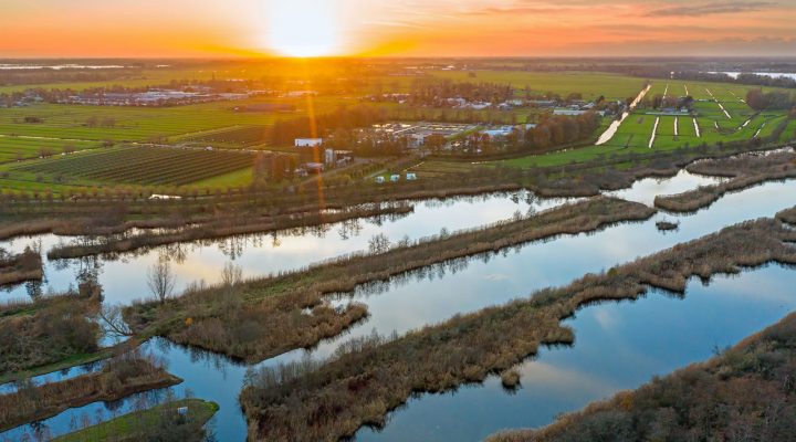 Luchtfoto van Nederlands landschap bij zonsondergang met waterlopen, groenstroken en bebouwing – ruimtelijke analyse en ecologische toetsing in het kader van